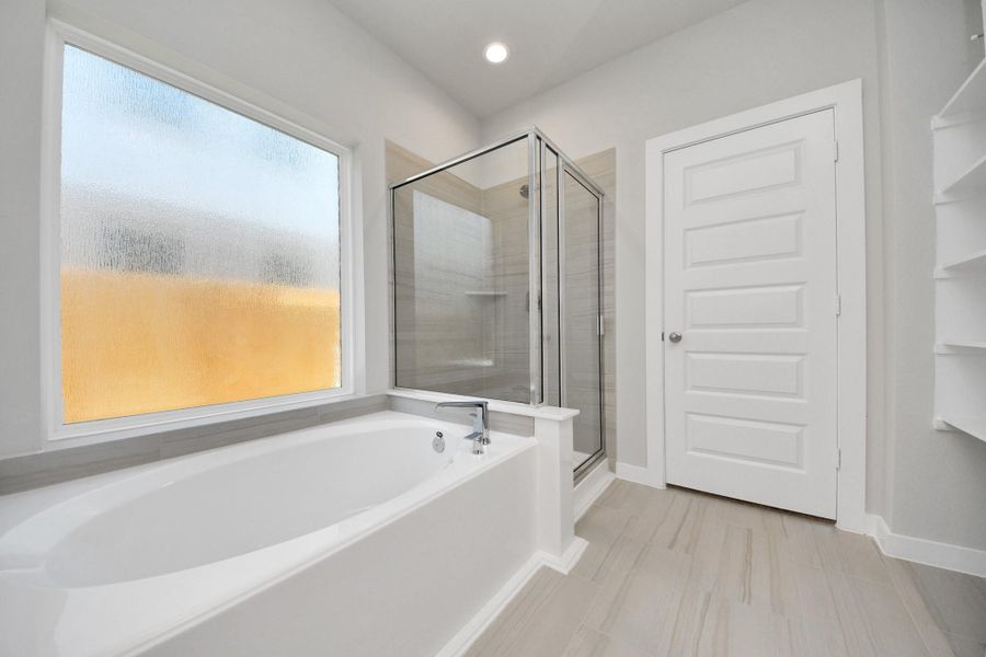 Delight in a spacious walk-in shower enveloped in stylish tile surround and unwind in a separate garden tub adorned with custom detailing. Sample photo of completed home with similar floor plan. Actual colors and selections may vary. Delight in a spacious walk-in shower enveloped in stylish tile surround and unwind in a separate garden tub adorned with custom detailing. Sample photo of completed home with similar floor plan. Actual colors and selections may vary.