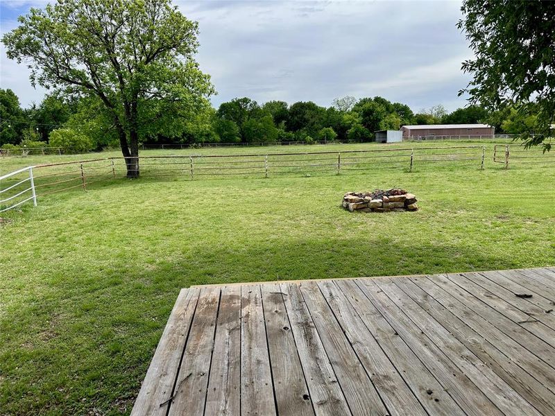 View of yard with an outdoor fire pit, a rural view, and view of wooded area
