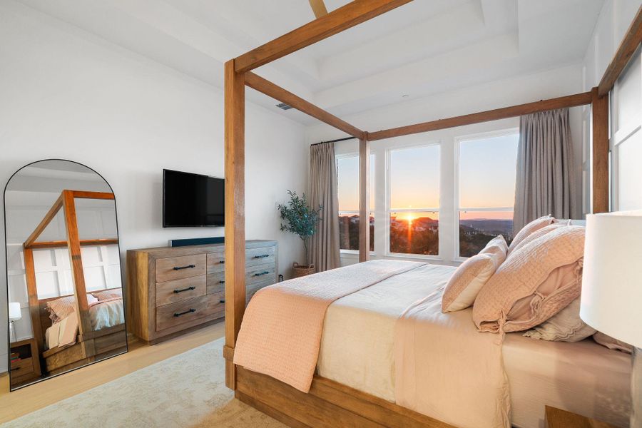 Spacious bedroom with light wood-finish flooring, white walls, and a multi-panel window overlooking a distant landscape Spacious bedroom with light wood-finish flooring, white walls, and a multi-panel window overlooking a distant landscape