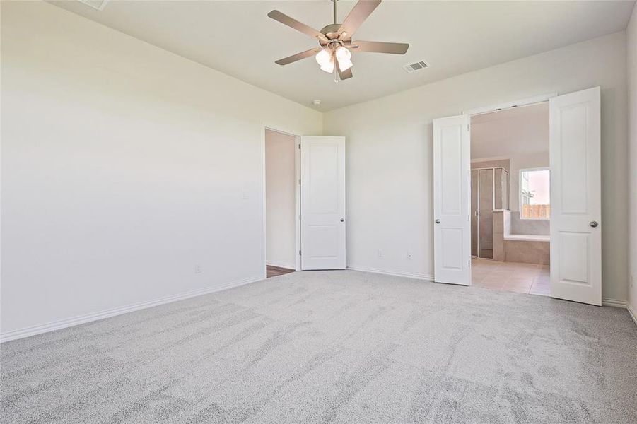 Unfurnished bedroom featuring light carpet, ceiling fan, and ensuite bathroom