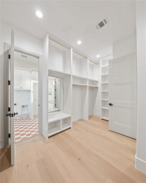 Walk in closet with light wood-style flooring Walk in closet with light wood-style flooring