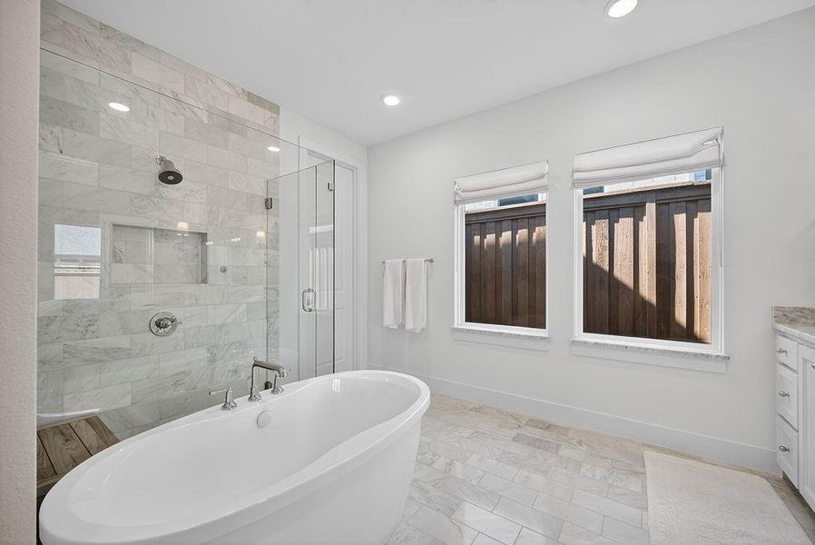 Bathroom with vanity, a shower stall, a freestanding tub, recessed lighting, and light marble finish flooring Bathroom with vanity, a shower stall, a freestanding tub, recessed lighting, and light marble finish flooring