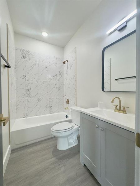 Full bathroom featuring wood-type flooring, vanity, toilet, and tiled shower / bath combo