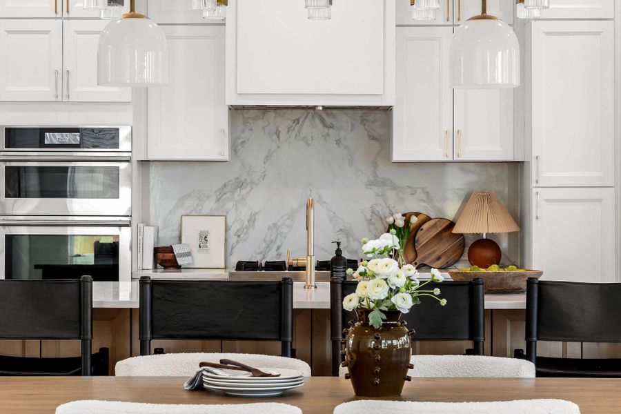 Kitchen with white cabinetry, double oven, pendant lighting, and backsplash