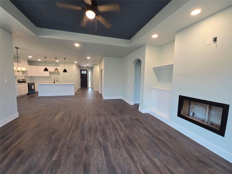 Unfurnished living room with recessed lighting, dark wood finished floors, a ceiling fan, arched walkways, and a fireplace