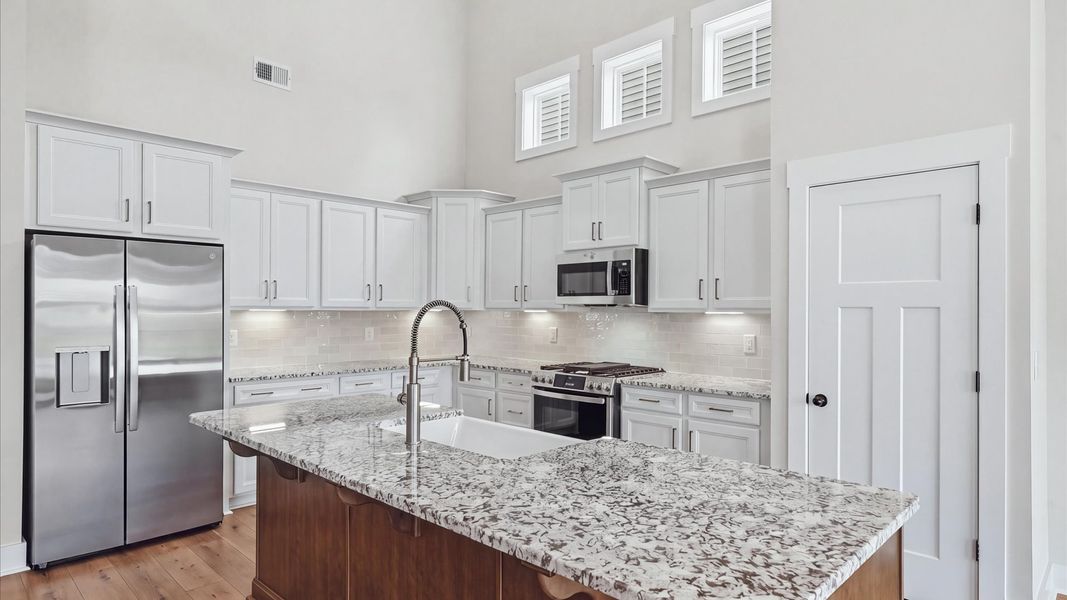 Exclusive DRB Homes kitchen with a 9-foot island, elevated finishes, and granite countertops in a prime location