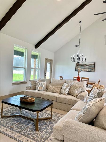 Living room with beamed ceiling, high vaulted ceiling, a chandelier, and a ceiling fan