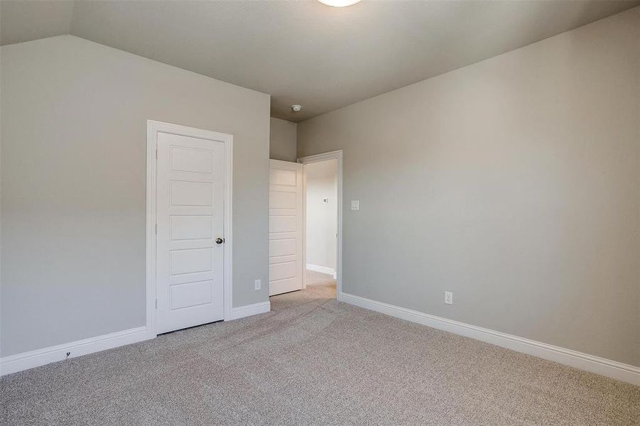 Unfurnished bedroom featuring light carpet, vaulted ceiling, and a closet