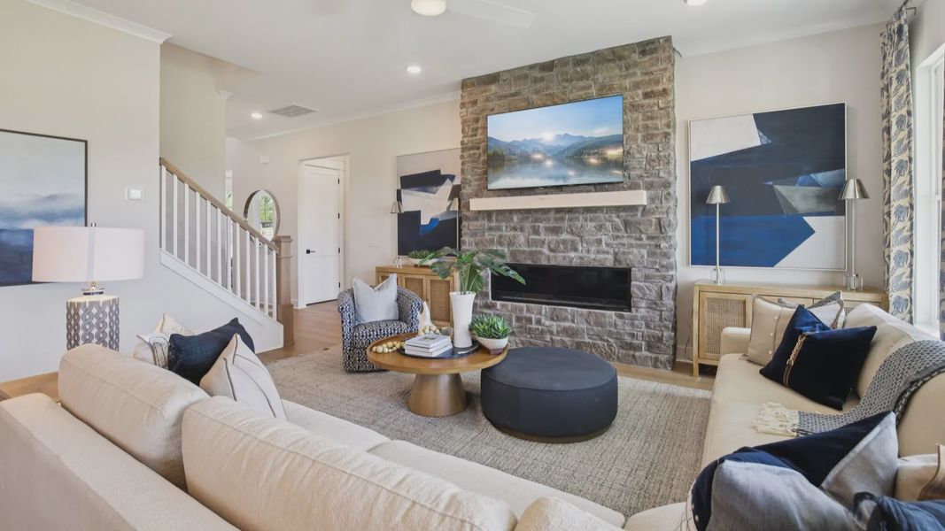 Large living room setup centered around stone fireplace with abundant natural light