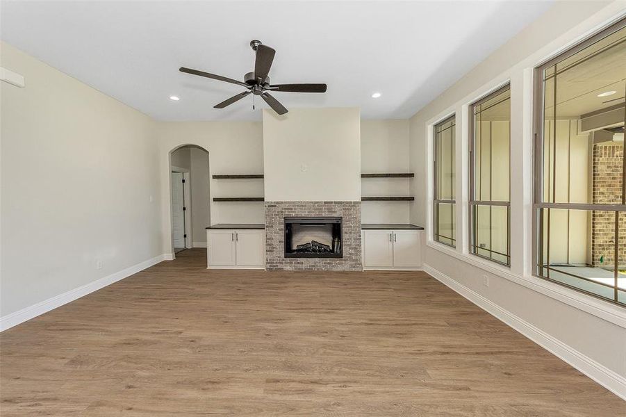 Unfurnished living room with ceiling fan, light hardwood / wood-style floors, and a brick fireplace