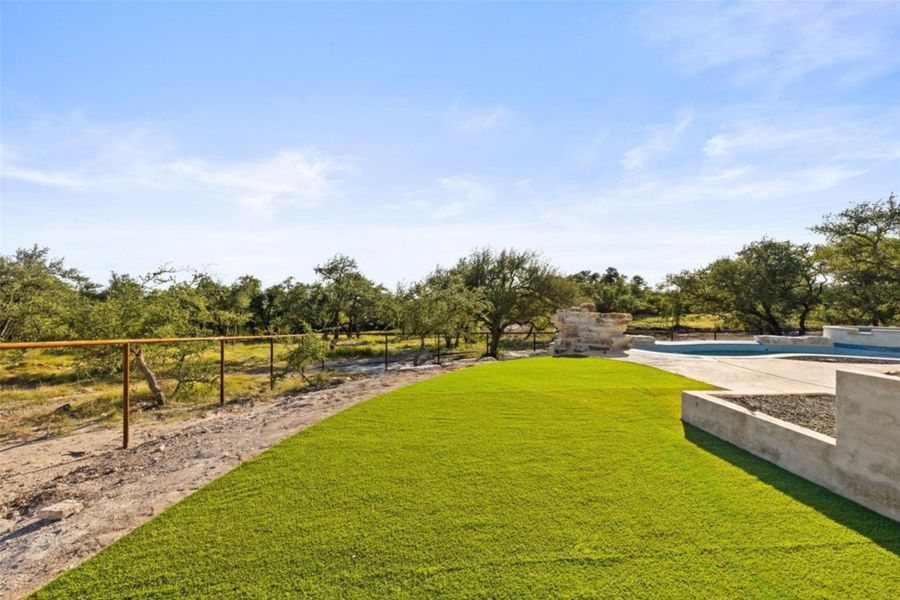 A pristine lawn stretches towards a tranquil pool area, embraced by native trees under a wide, open sky. A pristine lawn stretches towards a tranquil pool area, embraced by native trees under a wide, open sky.