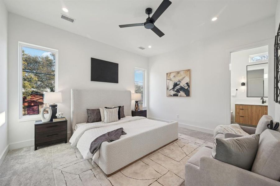 Bedroom featuring ensuite bath, light colored carpet, and ceiling fan