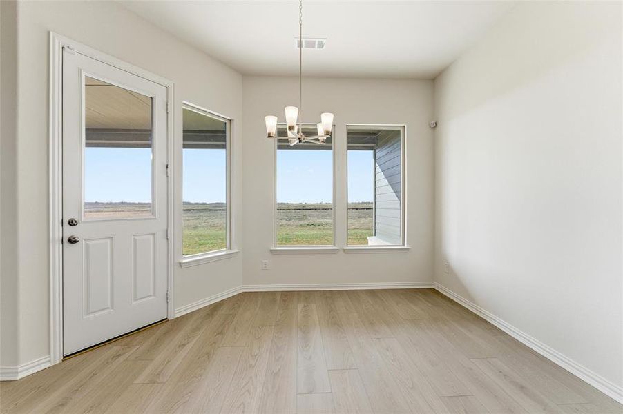 Unfurnished dining area with light wood finished floors and a chandelier
