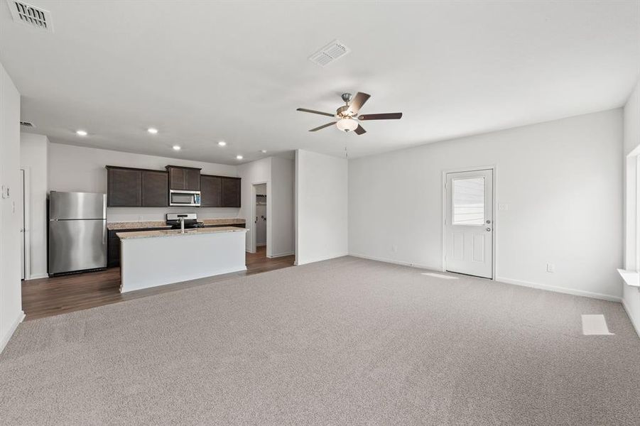 Living room with ceiling fan and light carpet