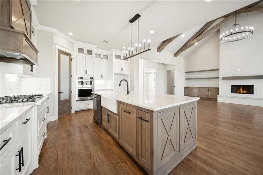 Kitchen with sink, light stone counters, a center island with sink, appliances with stainless steel finishes, and white cabinets