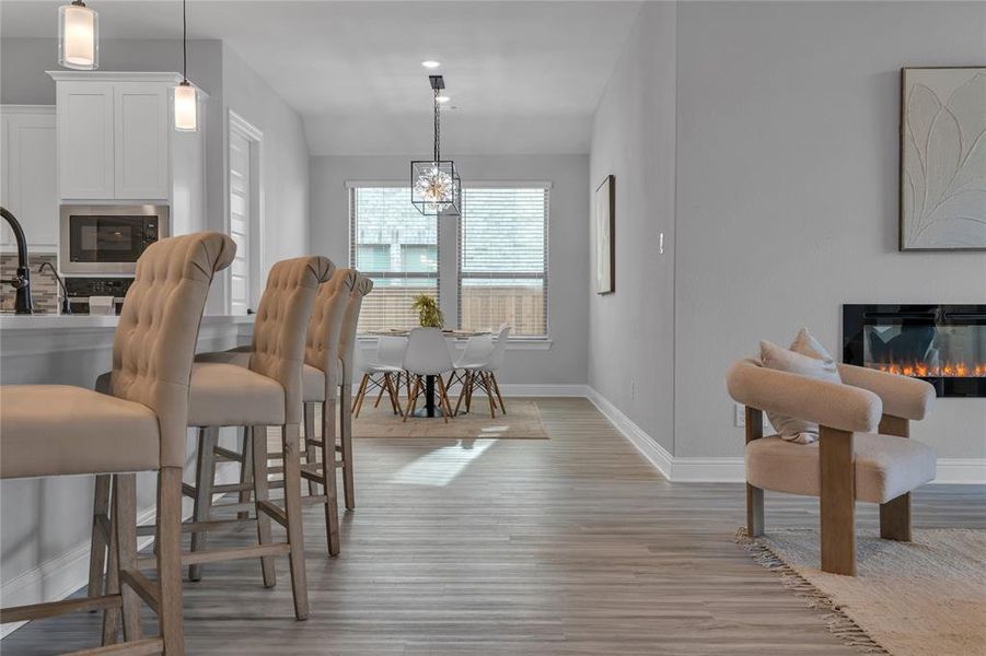 Dining room with a glass covered fireplace, light wood finished floors, and a chandelier Dining room with a glass covered fireplace, light wood finished floors, and a chandelier