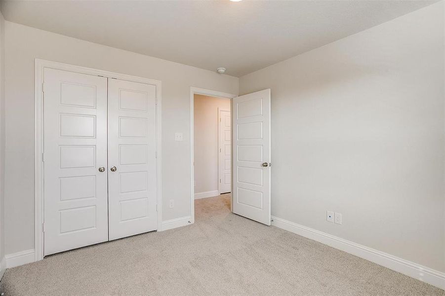 Unfurnished bedroom with a closet, light colored carpet, and baseboards