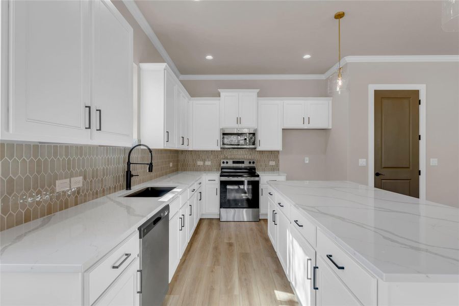 Kitchen with stainless steel appliances, light stone counters, a center island, white cabinetry, and crown molding
