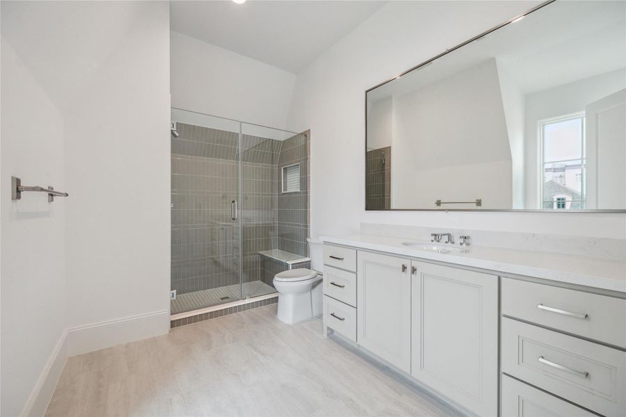 Oversized bathroom features glass-framed walk-in shower with niche, expansive mirror, and excess storage and counter space. Oversized bathroom features glass-framed walk-in shower with niche, expansive mirror, and excess storage and counter space.
