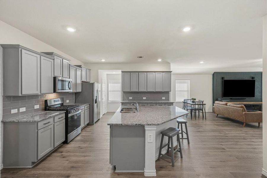 Kitchen featuring gray cabinetry, stainless steel appliances, light stone countertops, an island with sink, and recessed lighting Kitchen featuring gray cabinetry, stainless steel appliances, light stone countertops, an island with sink, and recessed lighting