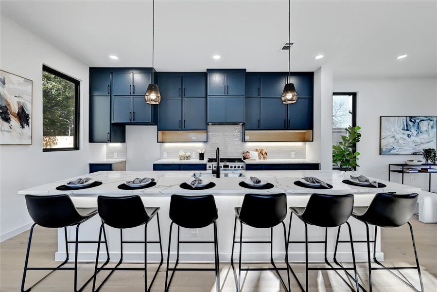 Kitchen with decorative backsplash, a breakfast bar area, blue cabinets, and a sink