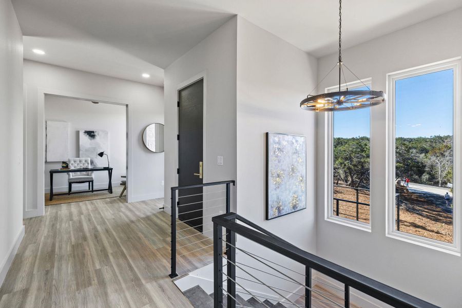 Corridor with light wood-type flooring, an upstairs landing, a notable chandelier, recessed lighting, and baseboards