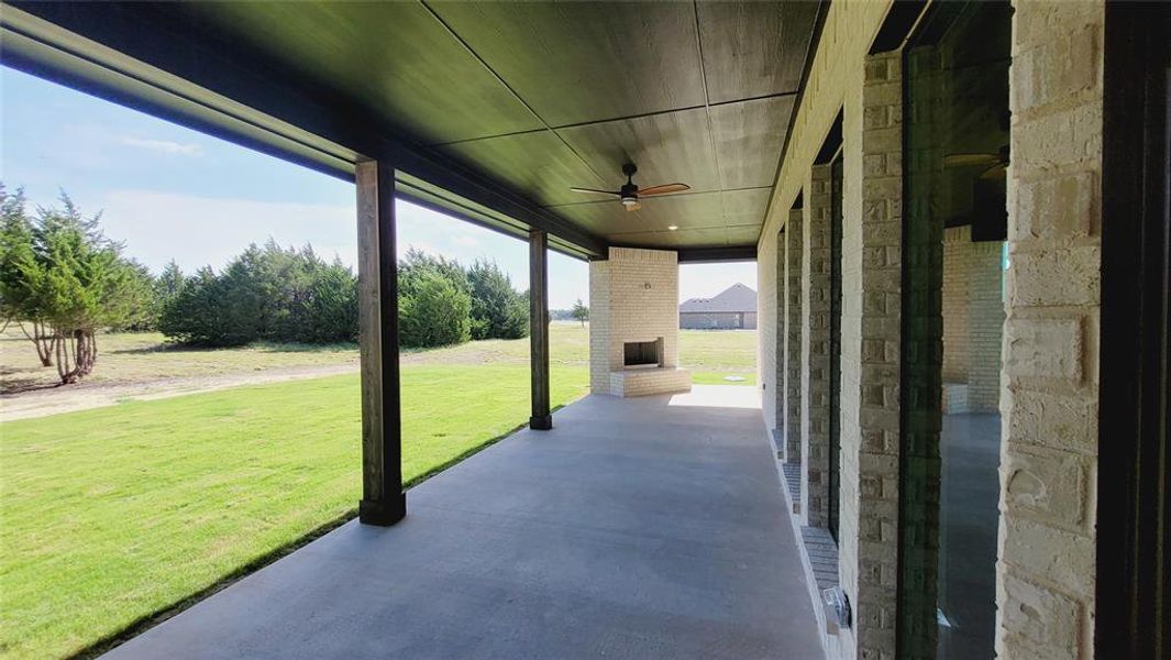 Expansive covered patio featuring a large outdoor fireplace, ceiling fan, and recessed lighting