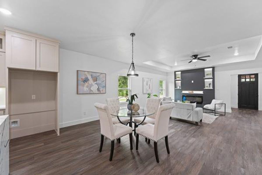 Open-concept living space featuring wood-finish flooring, a tray ceiling, and recessed lighting Open-concept living space featuring wood-finish flooring, a tray ceiling, and recessed lighting