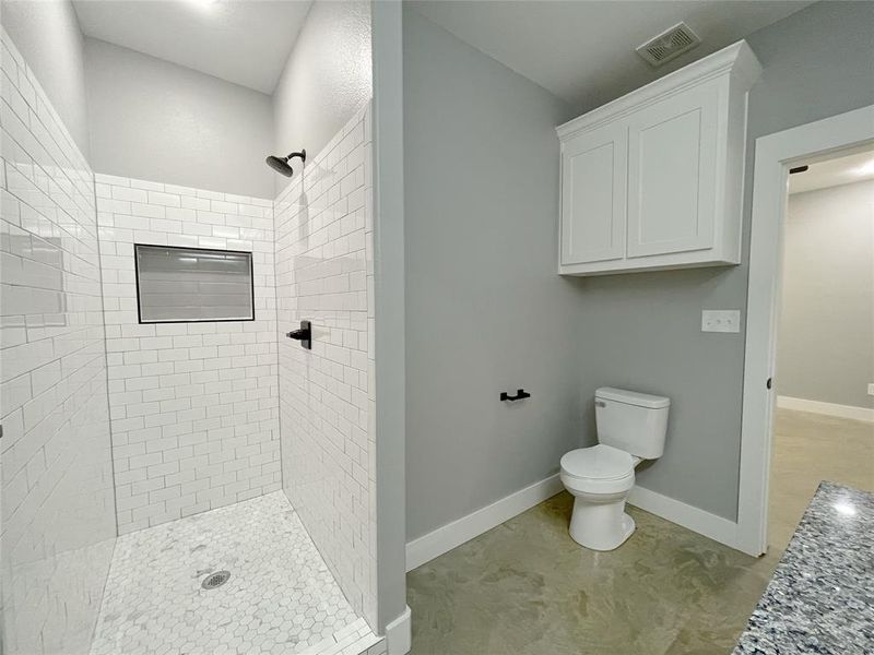 Bathroom featuring tiled shower and toilet