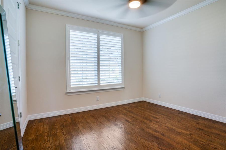 Empty room featuring ceiling fan, dark wood-type flooring, and ornamental molding