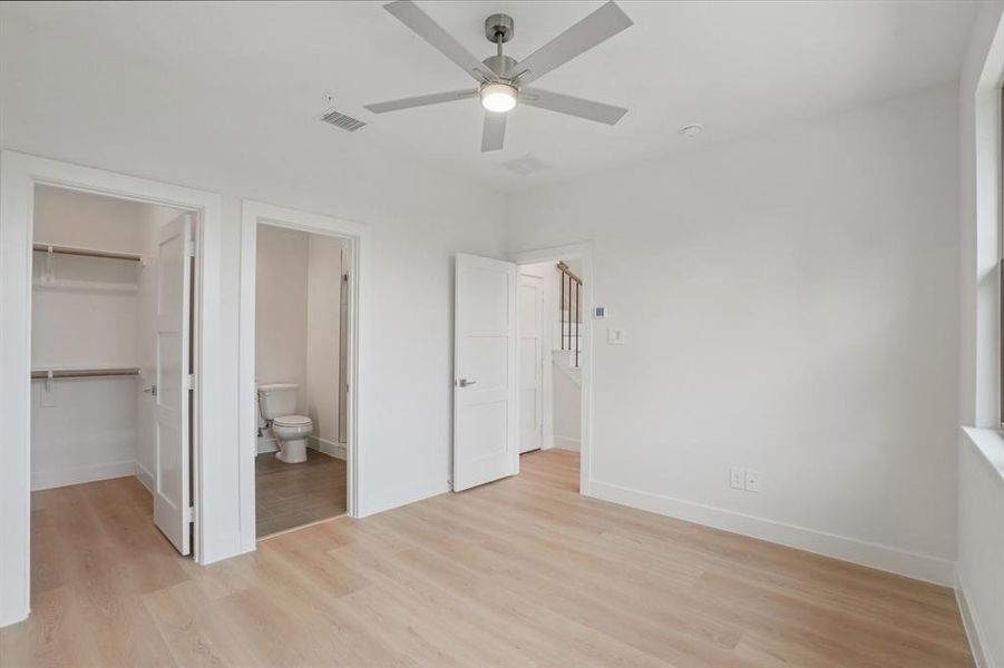 Unfurnished bedroom featuring light wood finished floors, a walk in closet, a ceiling fan, and ensuite bathroom
