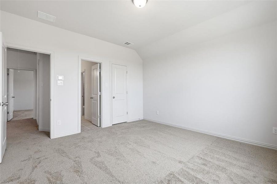 Spacious interior room featuring light-colored carpet, white walls, and multiple white panel doors