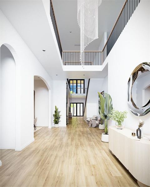 Foyer entrance featuring a chandelier, light wood-style flooring, arched walkways, and a towering ceiling Foyer entrance featuring a chandelier, light wood-style flooring, arched walkways, and a towering ceiling
