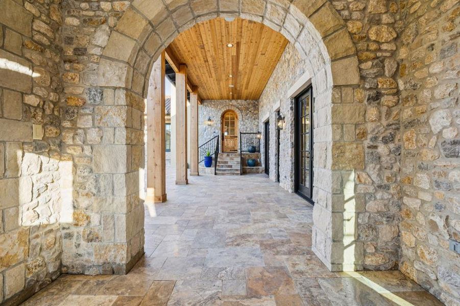 Hall featuring arched walkways, wood ceiling, recessed lighting, and stone tile flooring