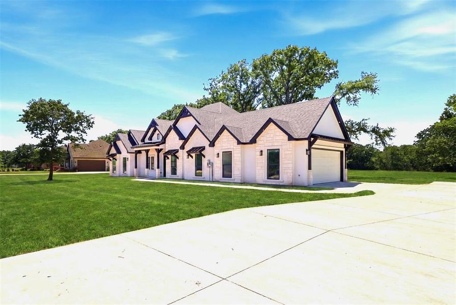 Contemporary white brick exterior with dark trim accents, multiple gables, a two-car garage, and a concrete driveway