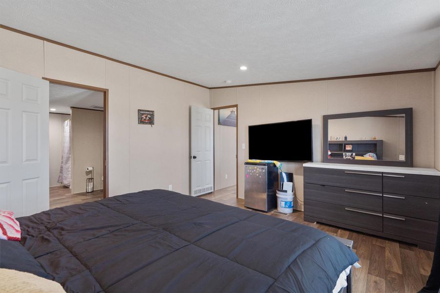 Smooth crown molding outlines this comfortable bedroom featuring low-maintenance wood-look vinyl flooring.