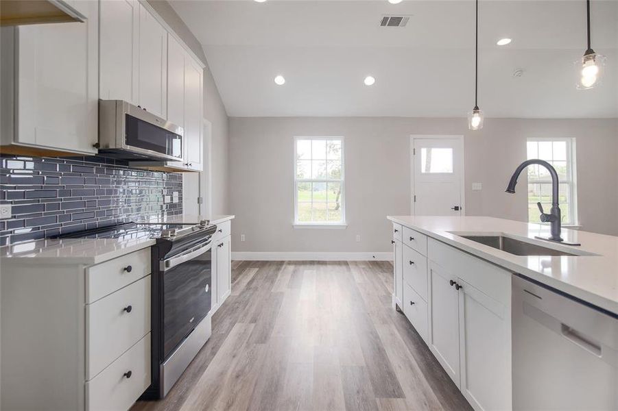 Featuring stainless appliances, quartz countertops, timelessly elegant cabinetry, tile backsplash, and a pantry.