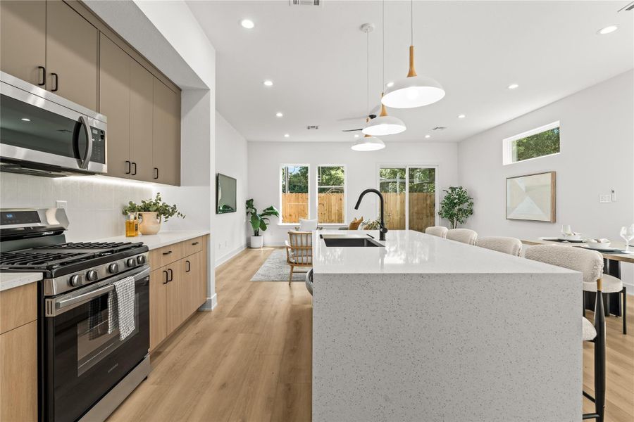 The layout completely connects the kitchen and living areas. The stainless steel gas range is surrounded by plenty of quartz counter space, keeping everything open. Anyone in the kitchen has a direct view and easy conversation range with guests in both the dining area and the living room.