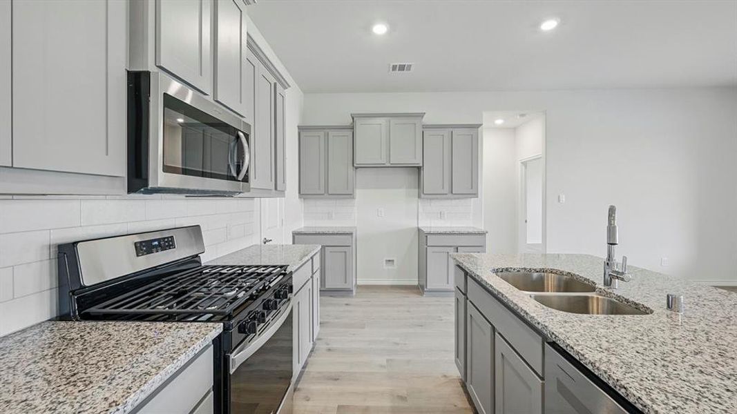 Kitchen with stainless steel appliances, gray cabinetry, tasteful backsplash, light stone countertops, and recessed lighting