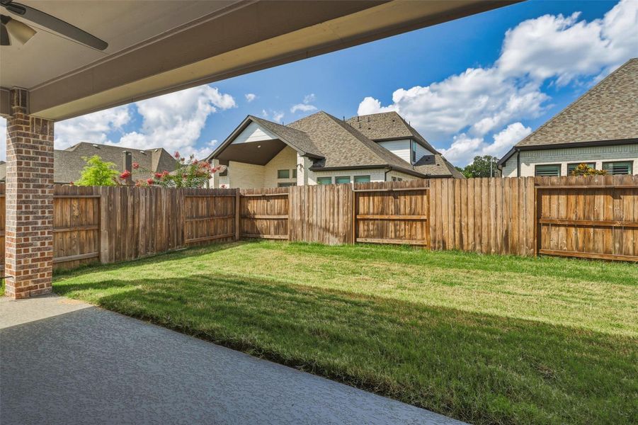 Another patio perspective showcases the home's spacious backyard and covered entertaining area. The private fenced yard provides an ideal setting for relaxing, dining outdoors, or enjoying time with family and friends.
