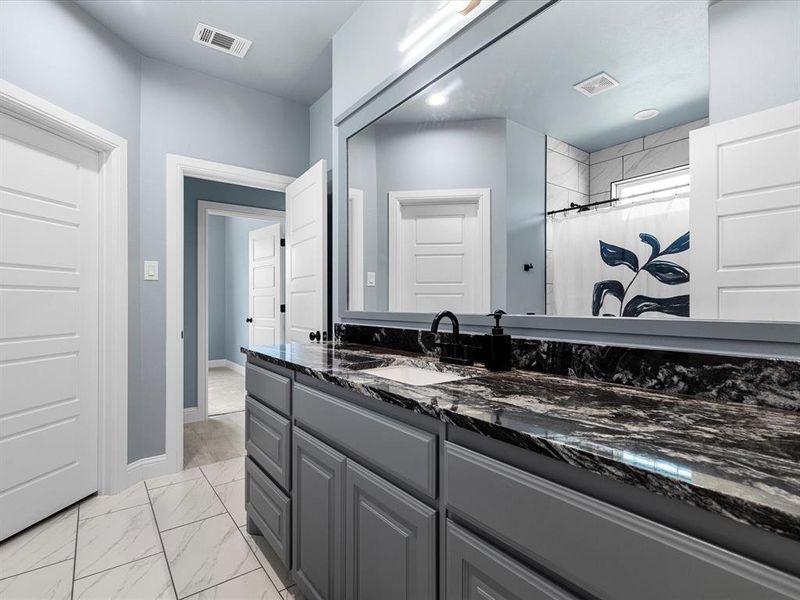 Full bath featuring vanity, light marble finish floors, and a shower with curtain Full bath featuring vanity, light marble finish floors, and a shower with curtain