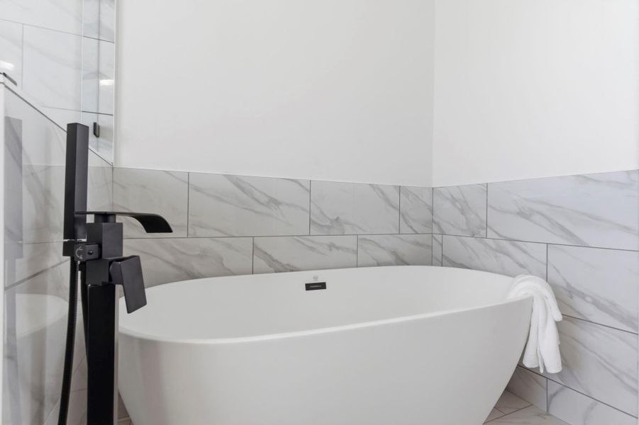 Spa-like primary bathroom featuring double sinks, a soaking tub, and a separate shower for a luxurious daily experience.