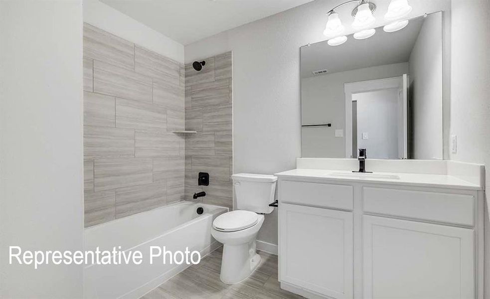 Full bathroom with hardwood / wood-style floors, vanity, toilet, and tiled shower / bath