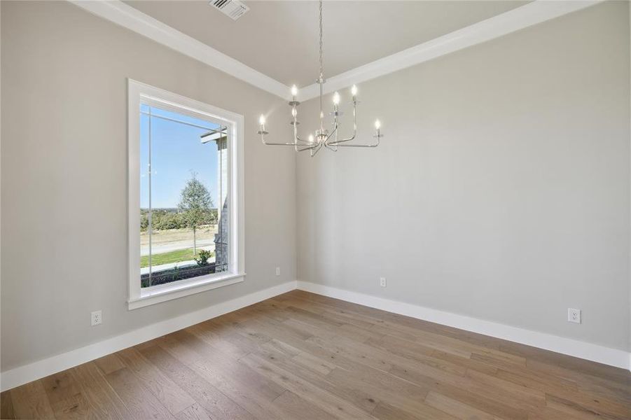 Spare room with light hardwood / wood-style floors and a notable chandelier