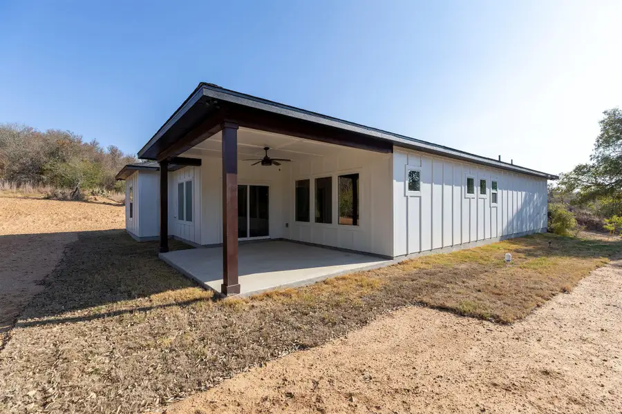 Rear view of property featuring ceiling fan, board and batten siding, and a patio area