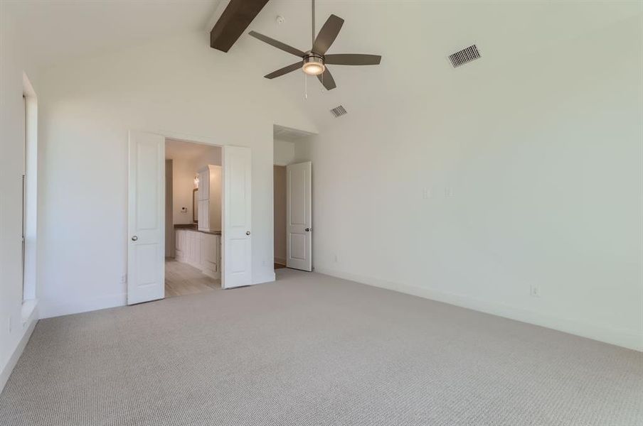 Unfurnished bedroom with ceiling fan, beamed ceiling, light carpet, and high vaulted ceiling