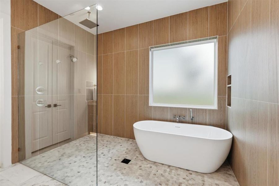 Bathroom featuring a tile shower, a freestanding bath, tile walls, and healthy amount of natural light