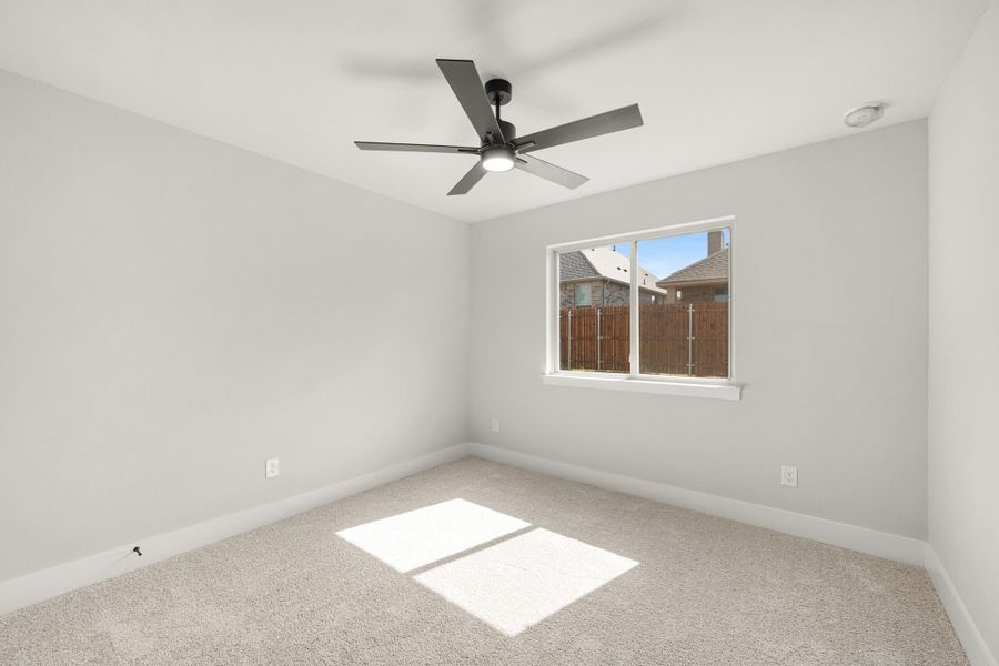 Empty bedroom with carpet flooring, ceiling fan, and single window with backyard view Empty bedroom with carpet flooring, ceiling fan, and single window with backyard view