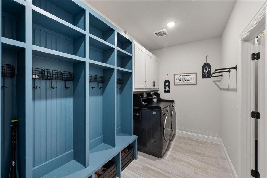 Laundry area with cabinet space, separate washer and dryer, and light wood-style floors