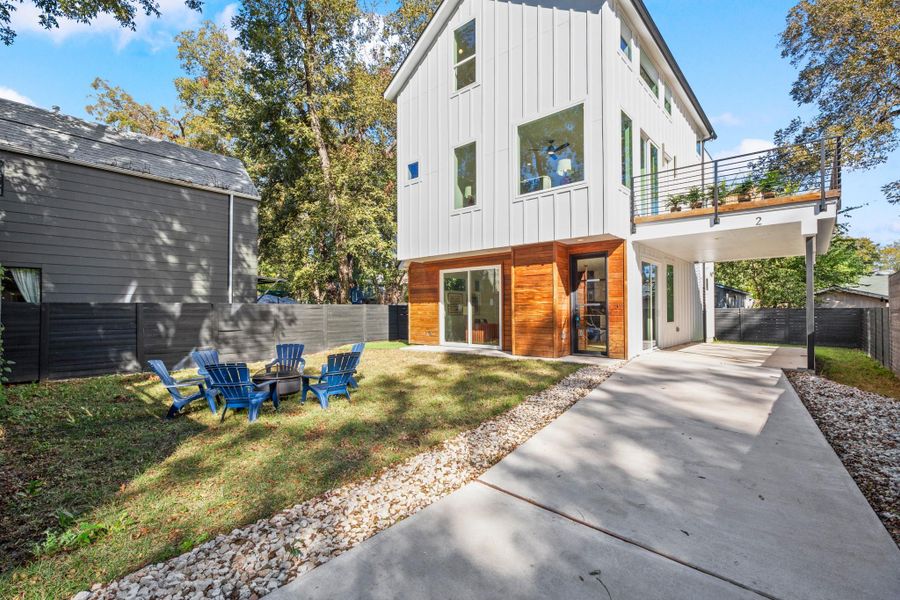 Rear view of property with a fenced backyard, a fire pit, and board and batten siding Rear view of property with a fenced backyard, a fire pit, and board and batten siding